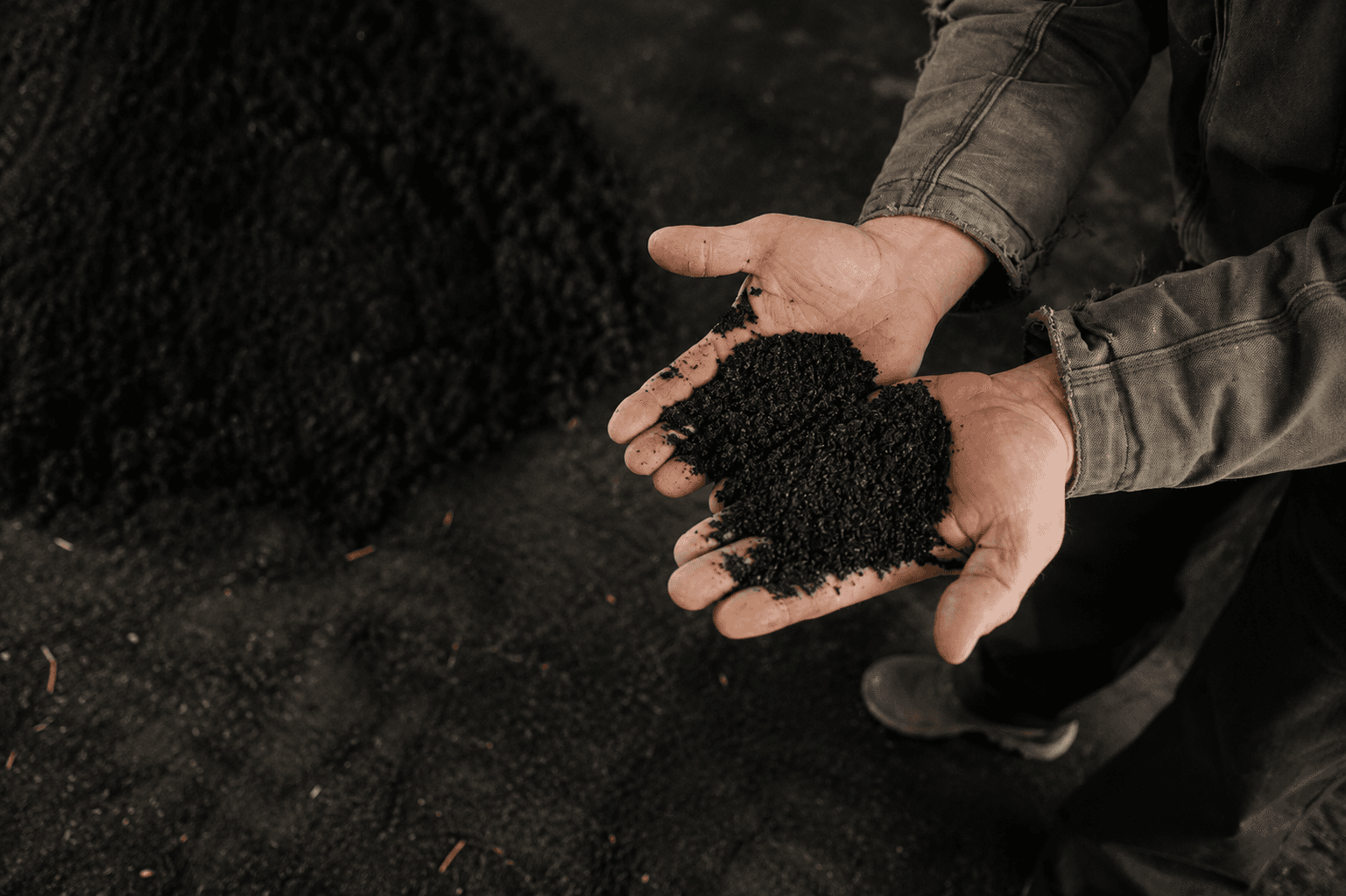 Hands holding acidified biochar poultry litter treatment material