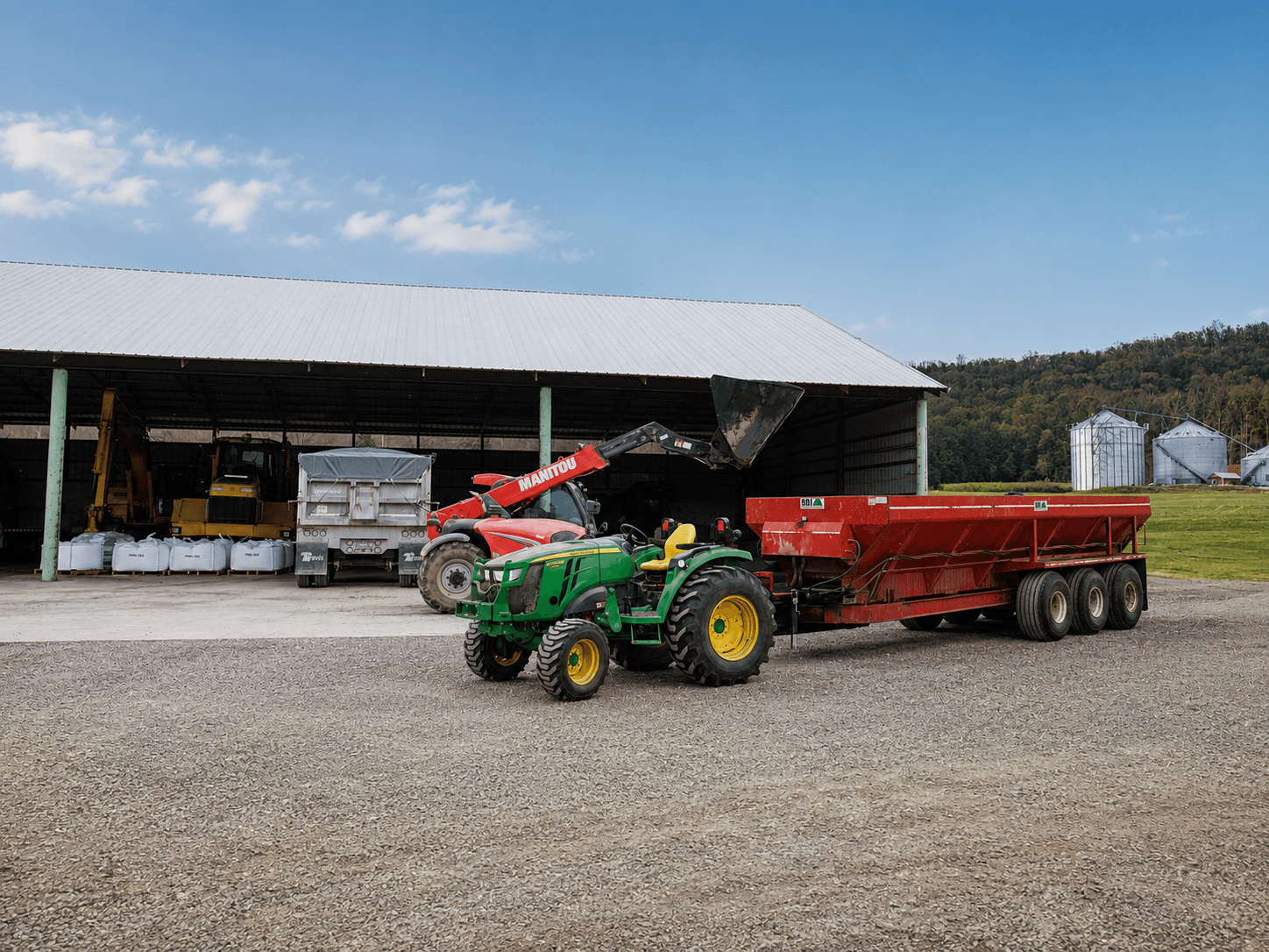 Poultry litter treatment spreader staged outside a commercial poultry house