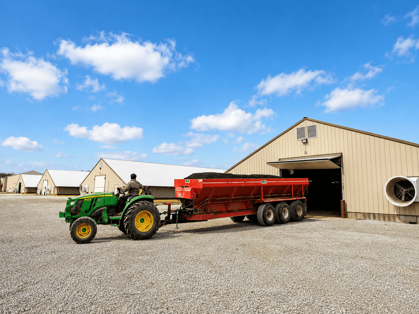 Tractor towing poultry litter treatment outside commercial poultry houses