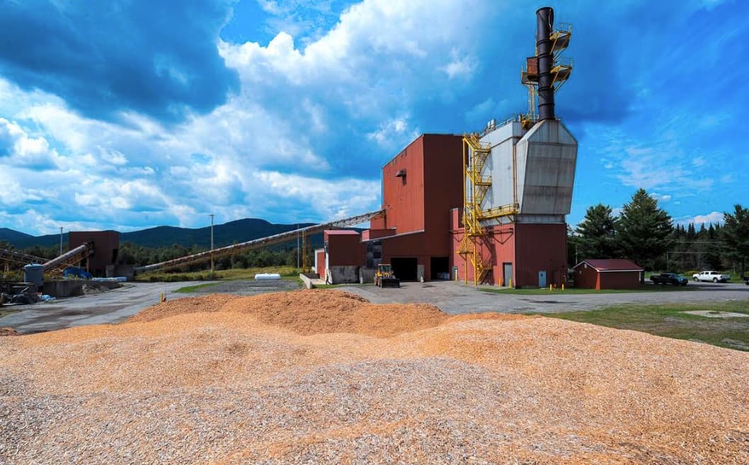 CMC data center facility showing industrial biomass processing plant with wood chips, conveyor belts, and sustainable energy infrastructure